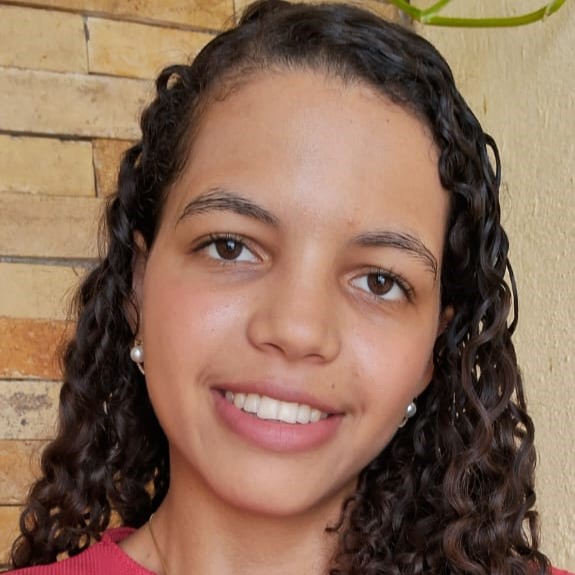 Foto de Dandara. Ela está com os cabelos soltos e uma blusa vermelha.